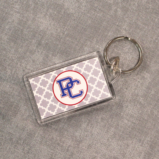 Picture of a rectangular acrylic keychain that has a grey and white diamond pattern background and then a white circle with the color block PC logo on it.