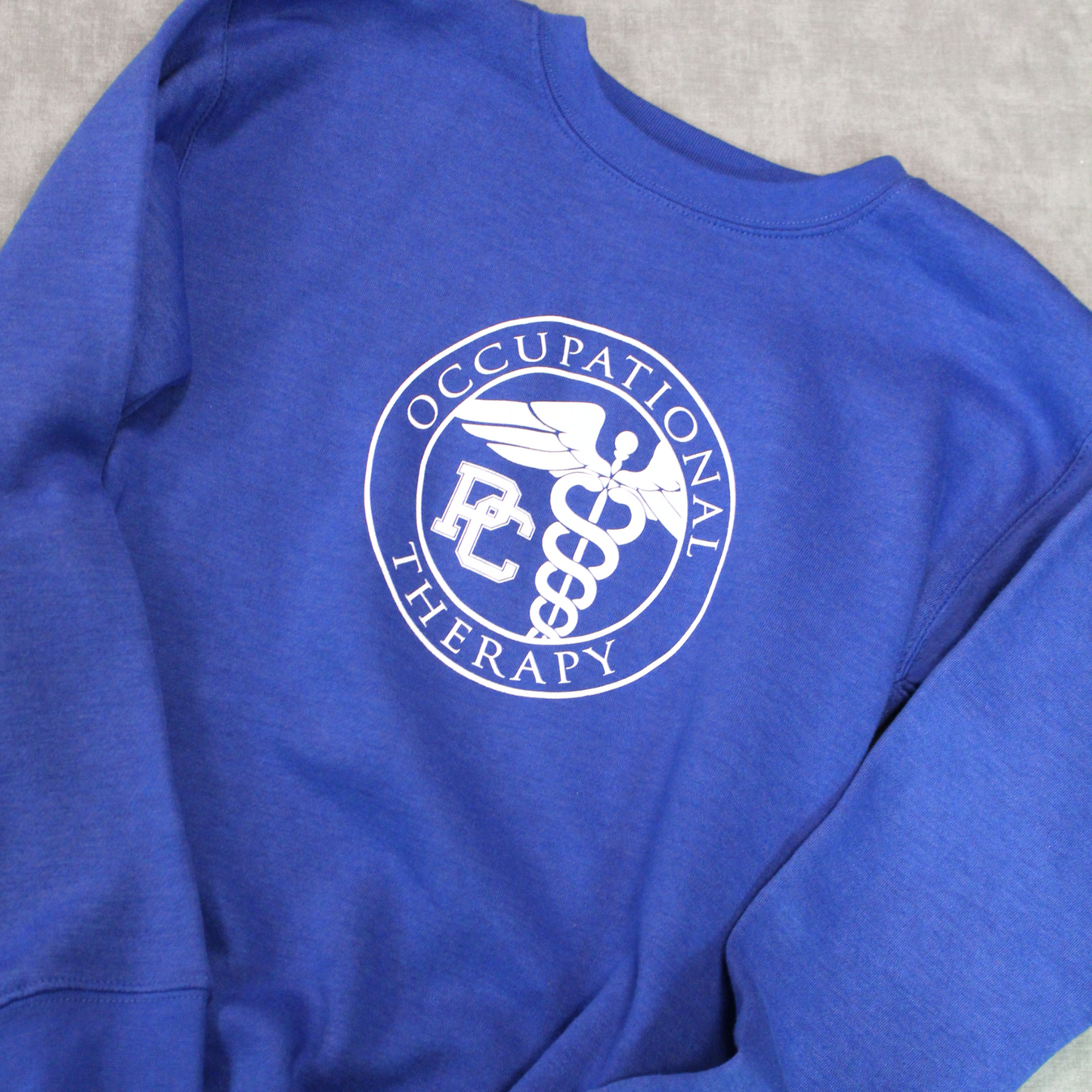 Another view of the royal blue crew with the Presbyterian College Occupational Therapy Badge screen printed in white on the front.