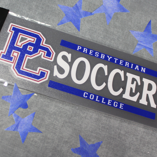A decal with a block PC logo and the text 'Presbyterian Soccer College' -the background of this product photo has blue stars on it