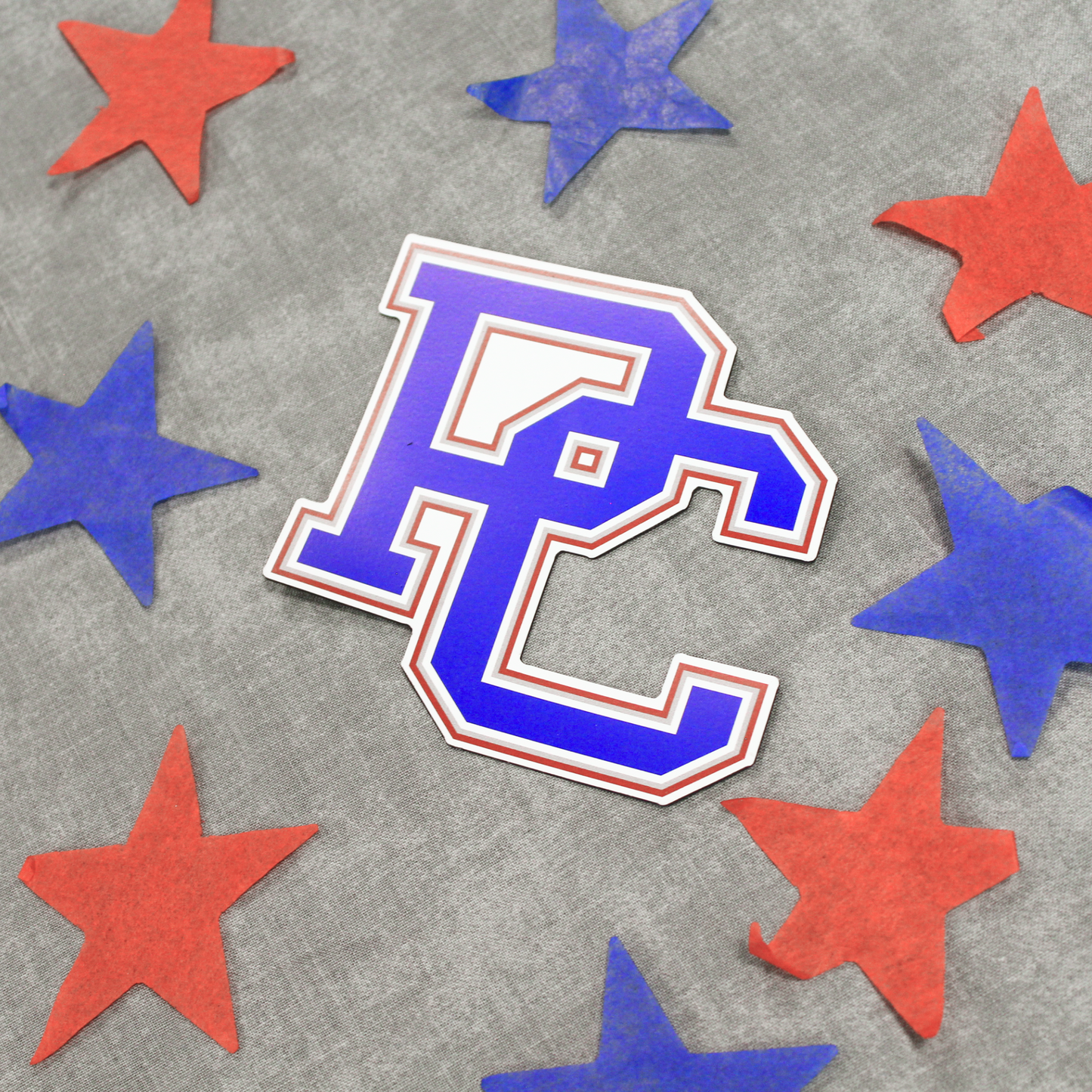 A picture of the Presbyterian College block 4 color PC logo magnet in blue, red, grey and white. The background of this image has blue and red stars in it.