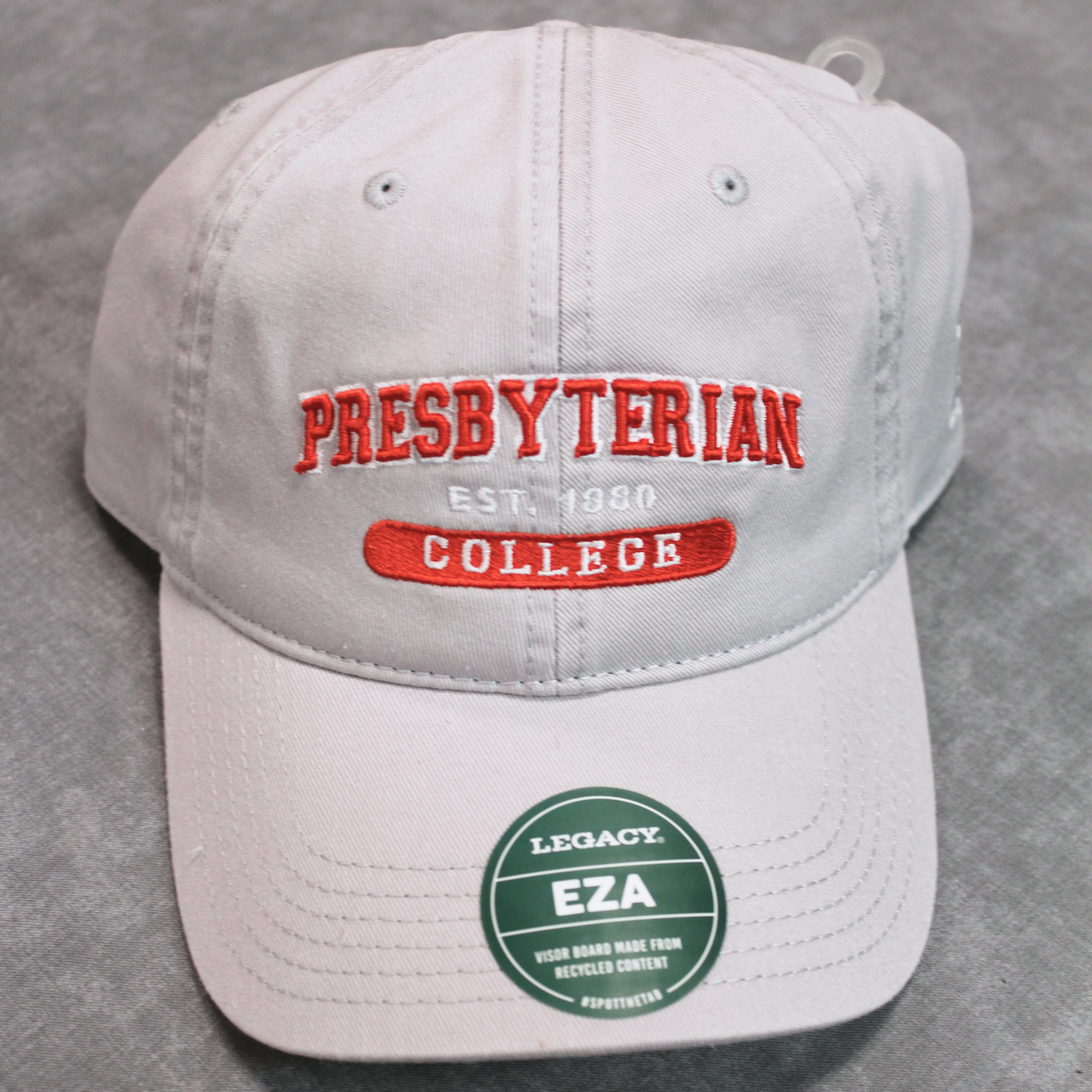 A silver grey baseball cap with the 'Presbyterian College' embroidered in red and white on the front.