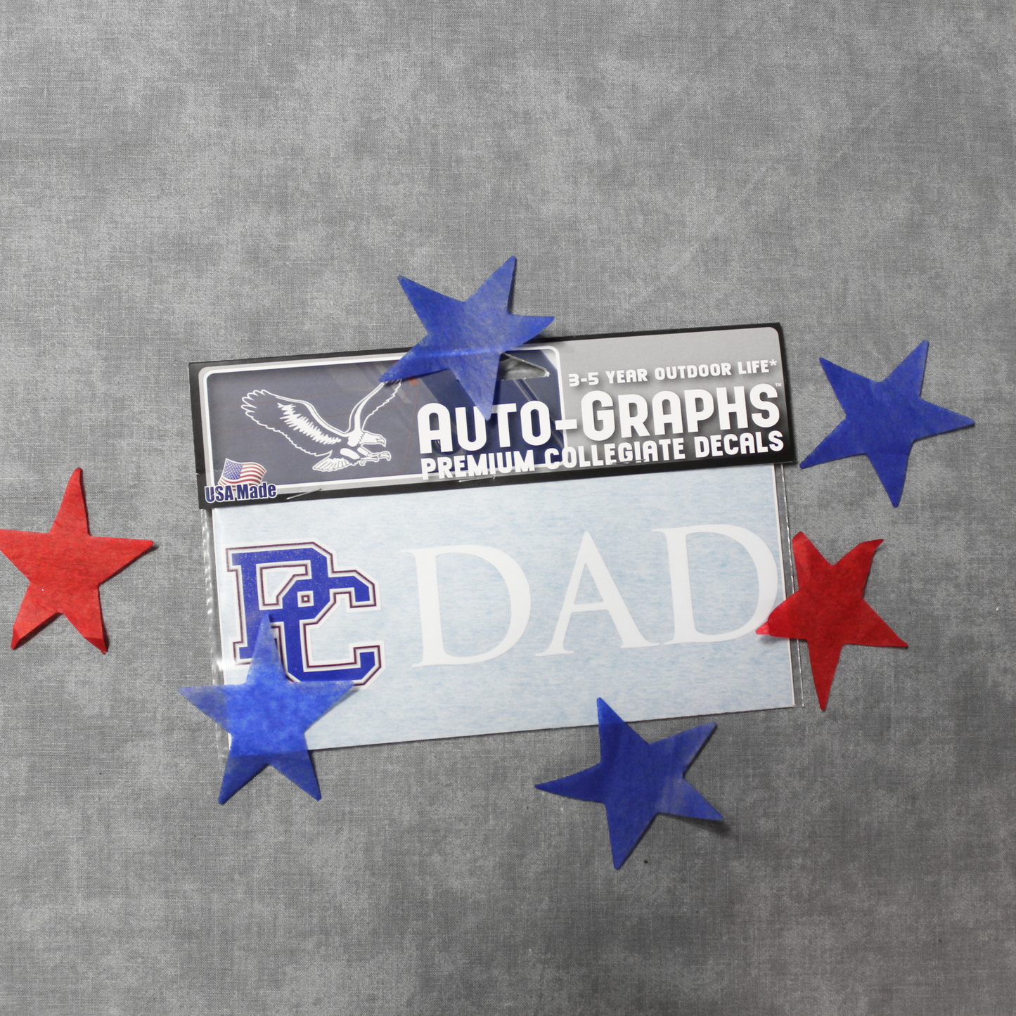 Product photo of a PC Dad decal that features a 4 color block PC logo and white lettering that spells out DAD. The product photo has blue and red stars surrounding the decal.