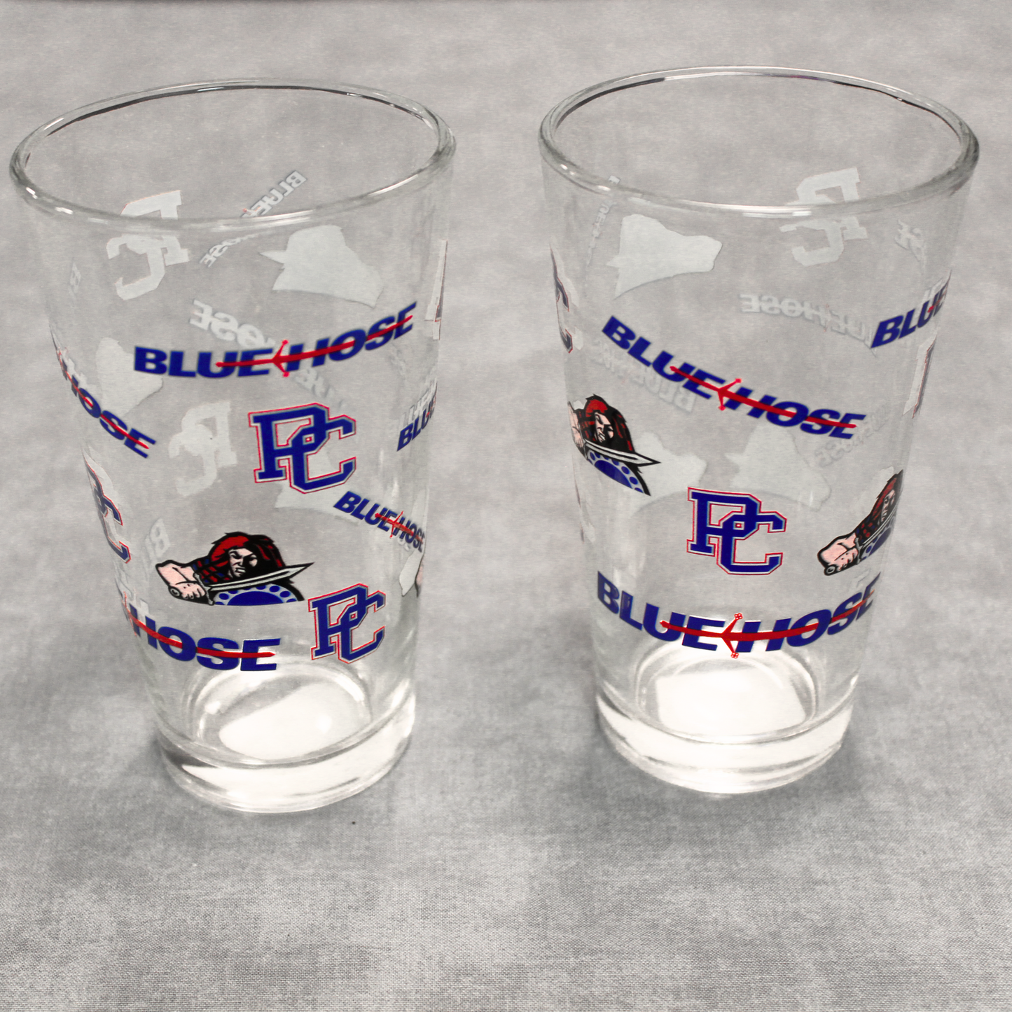 Two drinking glasses that feature the PC logo, Scotty the Scotsman Athletic logo, and the Blue Hose wordmark logo.