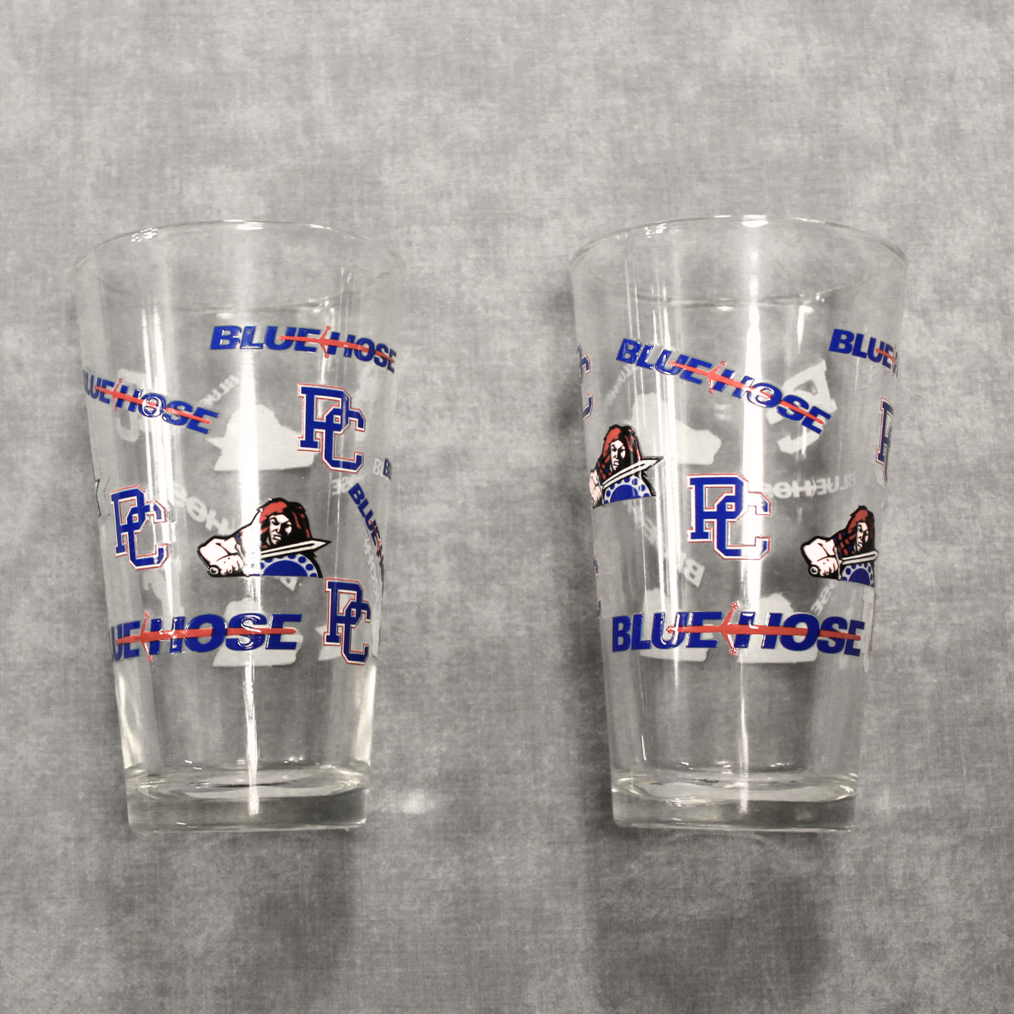 Another view of the two drinking glasses that feature the PC logo, Scotty the Scotsman Athletic logo, and the Blue Hose wordmark logo.
