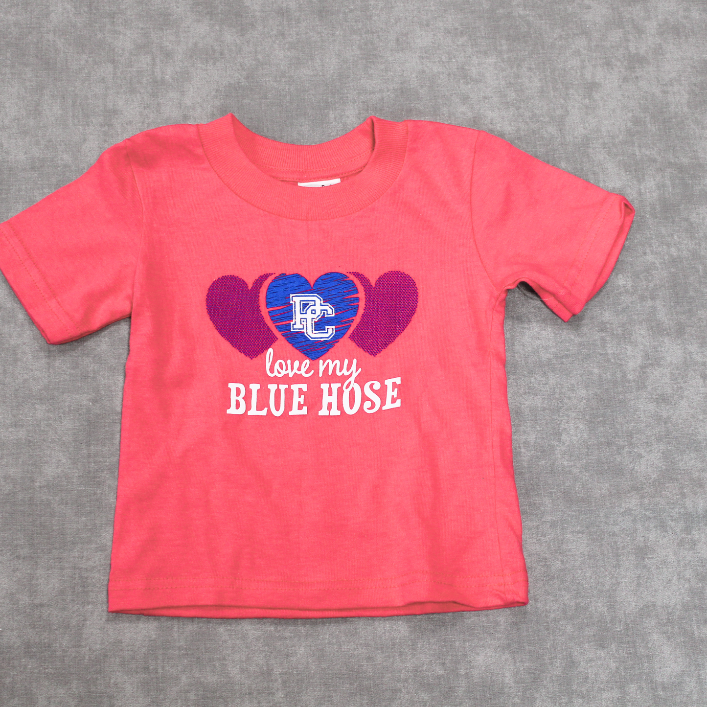 Hot pink infant t-shirt with a blue heart graphic and a white block PC logo on it with the words "love my blue hose" on it.