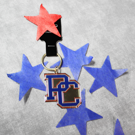 A picture of the brass keychain that features a blue, red, and white block PC logo in front of a backdrop of blue and red stars.