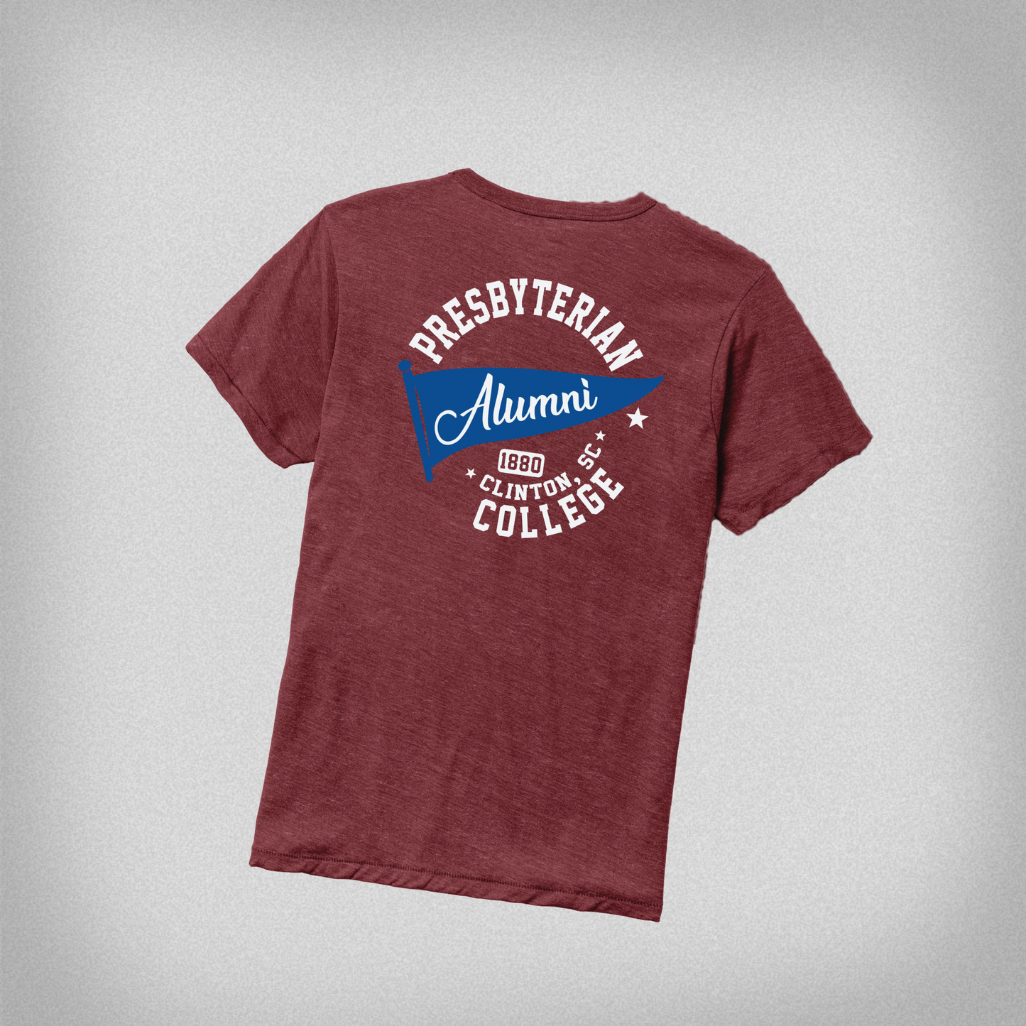 Picture of the back of the garnet red alumni tee, which features a white and navy blue screen print design on the back that has a bleu flag that says Alumni, and text surrounding the flag that says Presbyterian College, 1880, Clinton, SC