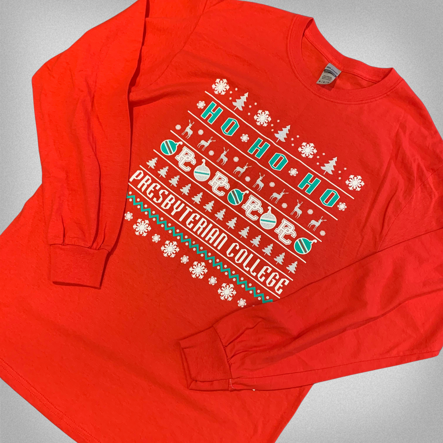 Red long sleeve shirt with white and green screen print that has christmas trees, snowflakes, deer, and ornaments along with "Ho Ho Ho" and "Presbyterian College"