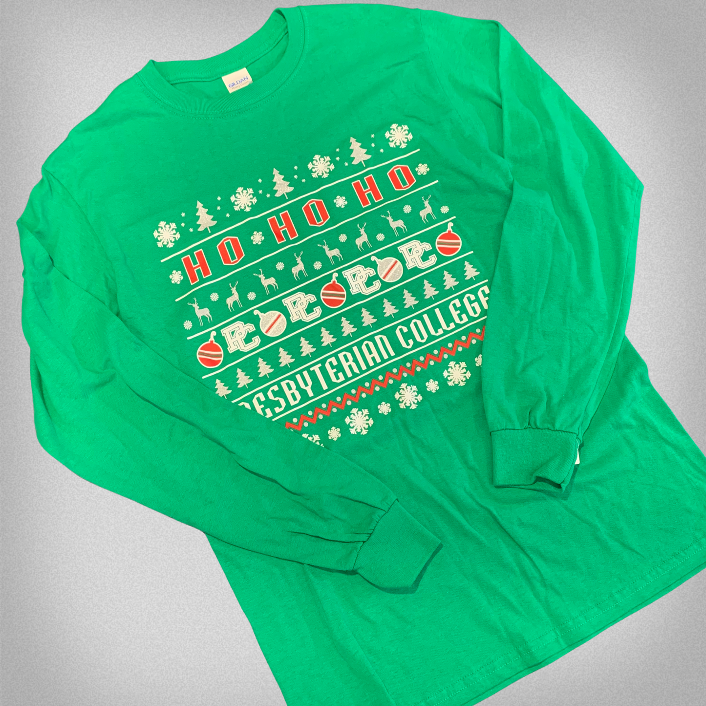 Green long sleeve t-shirt with red and white screen print graphic that says "Ho Ho Ho" and "Presbyterian College" along with christmas symbols like trees, snowflakes, deer, and ornaments.