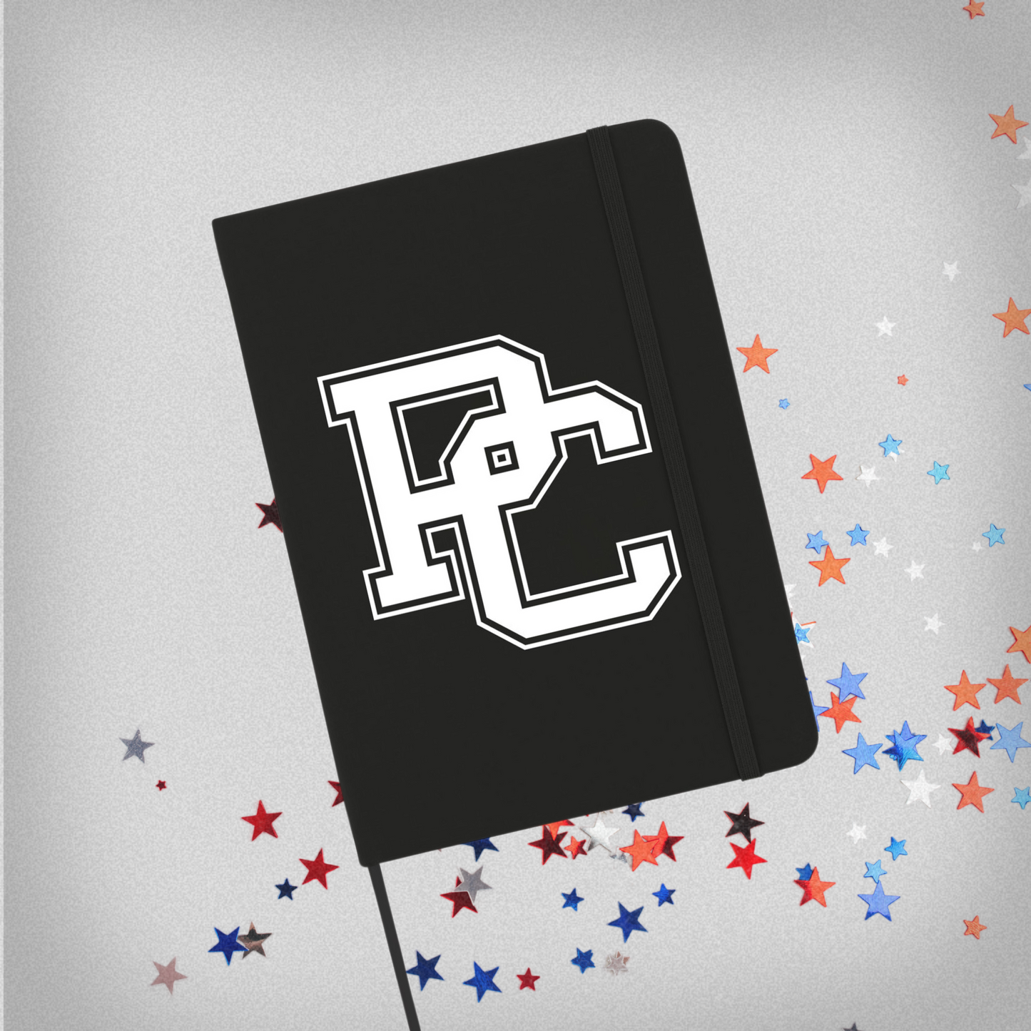 Black notebook with a white PC logo on the front. This product photo has red, white, and blue stars in the background.