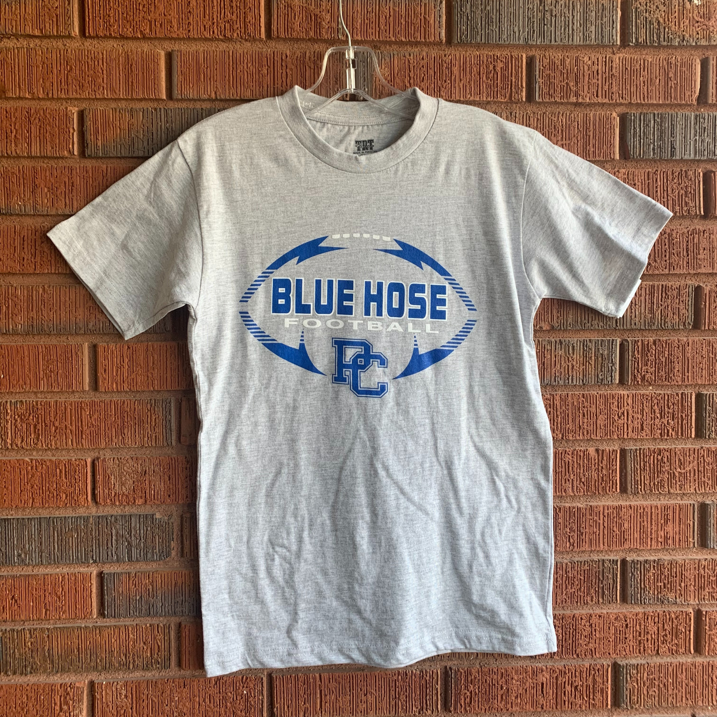Grey shirt with royal and white screen print design with a football and the words Blue Hose Football and a bloc PC on it.