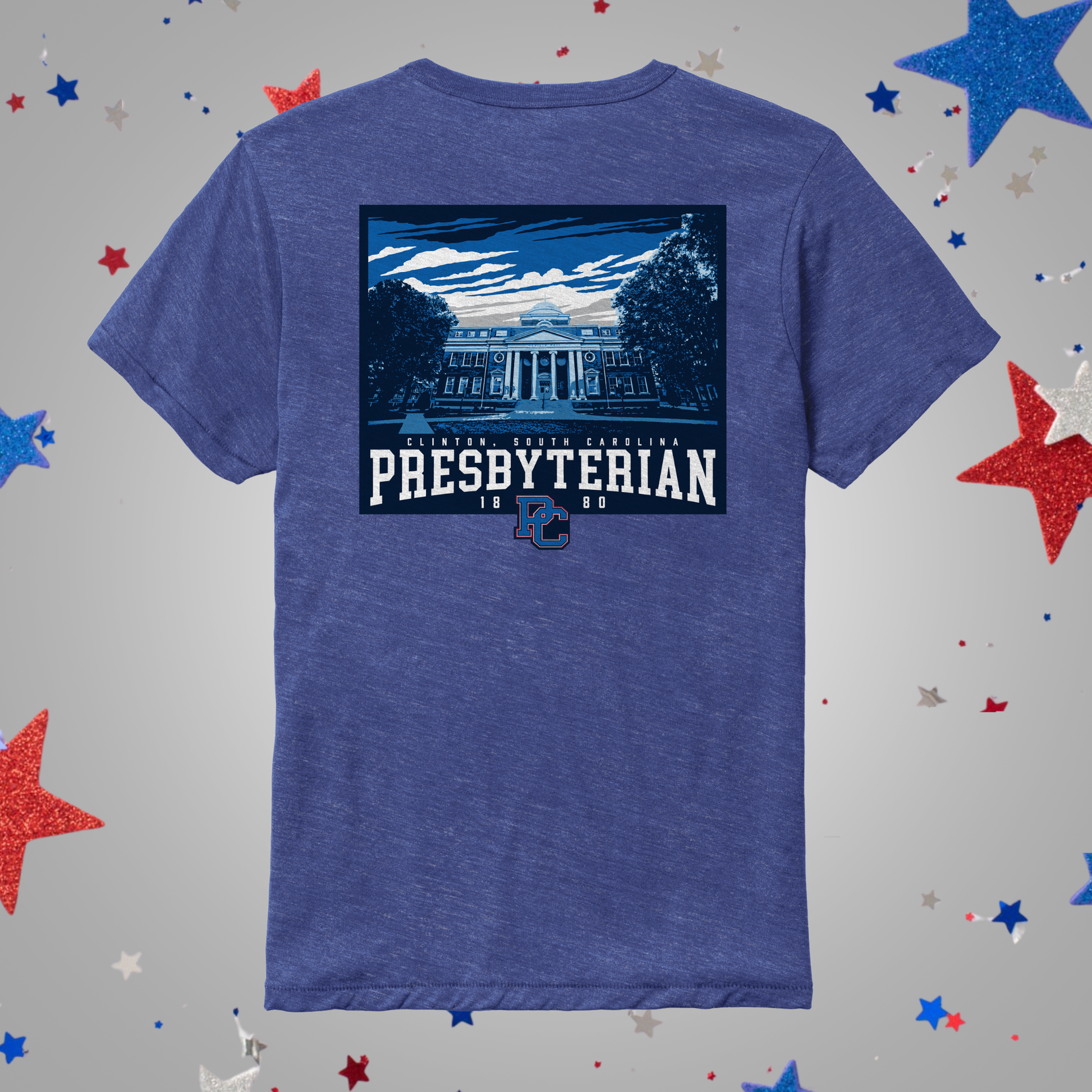 A heathered blue short-sleeve t-shirt shown from the back, featuring a large graphic print of a classical building with the text 'PRESBYTERIAN 1868' and a small blue 'PC' logo. The shirt is displayed on a light gray background decorated with scattered red, white, and blue glitter stars.
