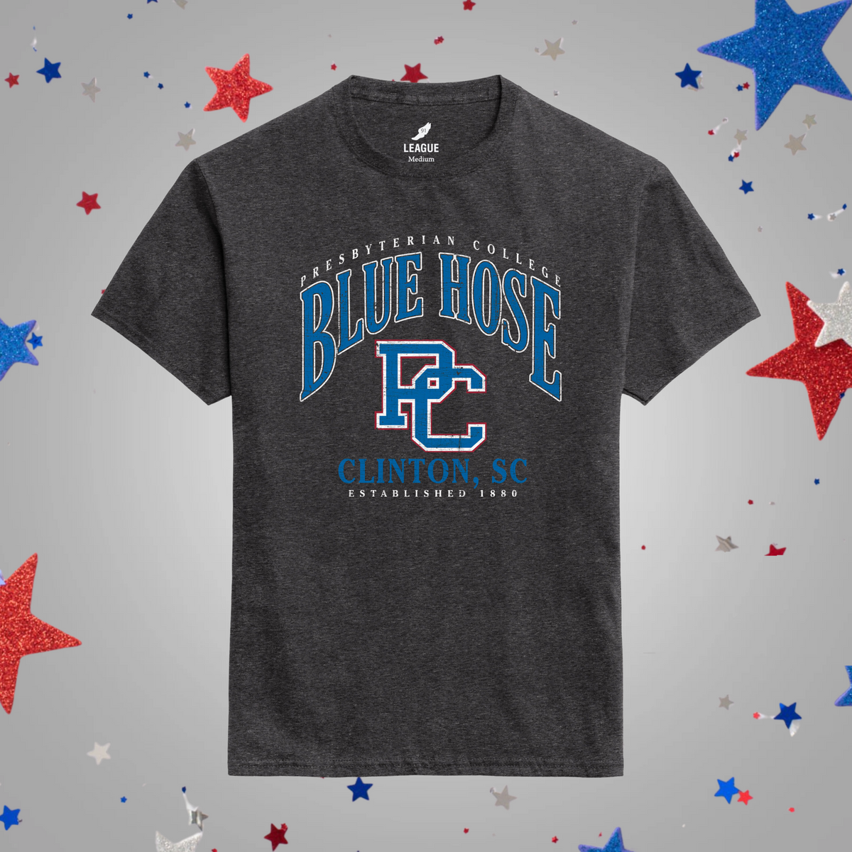 A dark heather black t-shirt with a blue and white 'Blue Hose' graphic on the front, displayed against a light gray background decorated with scattered red, white, and blue glitter stars.