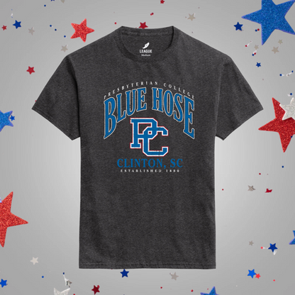 A dark heather black t-shirt with a blue and white 'Blue Hose' graphic on the front, displayed against a light gray background decorated with scattered red, white, and blue glitter stars.